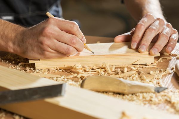 Menuisier en plein prise de mesure sur une planche en bois